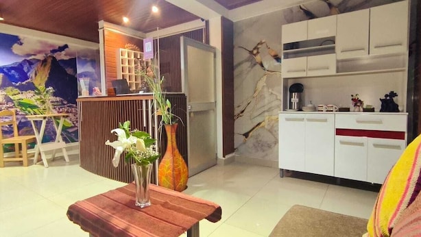 A modern interior with a reception desk, a mural, and a kitchen area. - Hotel La Florida  (Cusco)