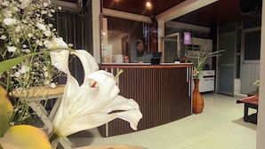 A reception area with a wooden counter, a large white flower arrangement, and a vase. - Hotel La Florida  (Cusco)