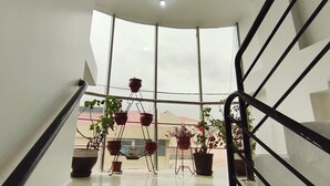 A modern staircase with a glass railing, leading to a balcony with potted plants. - Hotel La Florida  (Cusco)