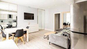 A modern living room with a grey sofa, a wooden coffee table, and a large flat-screen TV mounted on the wall. - Stylish Bayswater Flat with Outdoor Space (London)