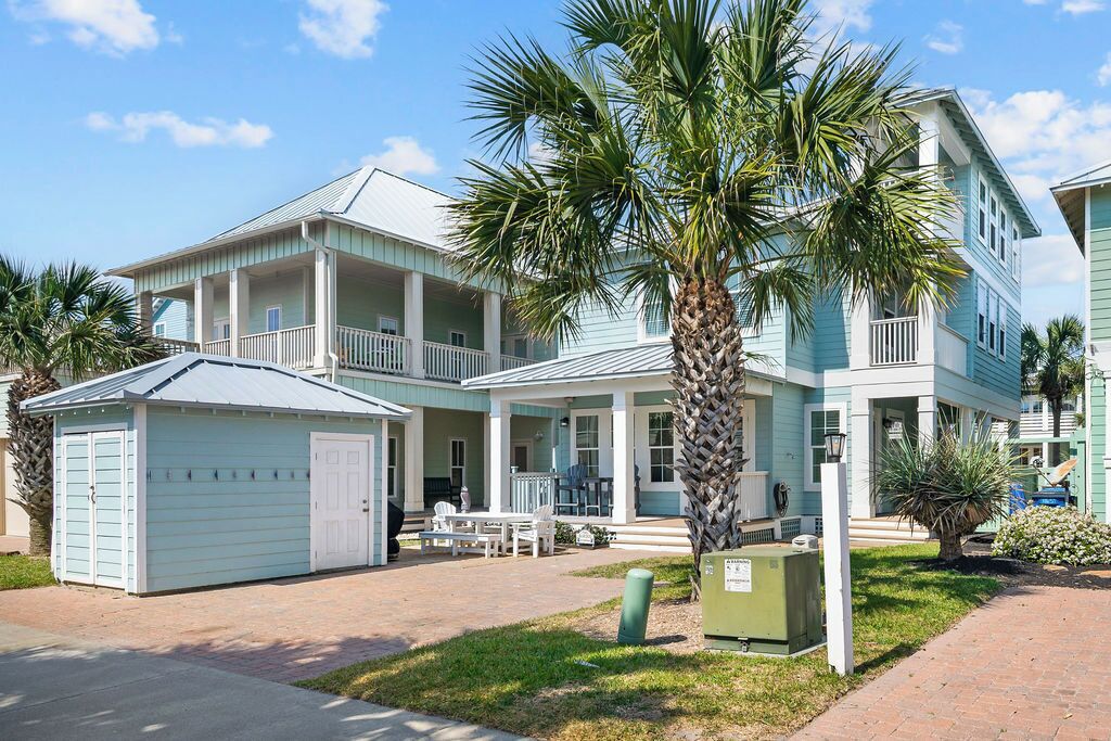 A two-story building with a porch, a garage, and a palm tree in the front yard.