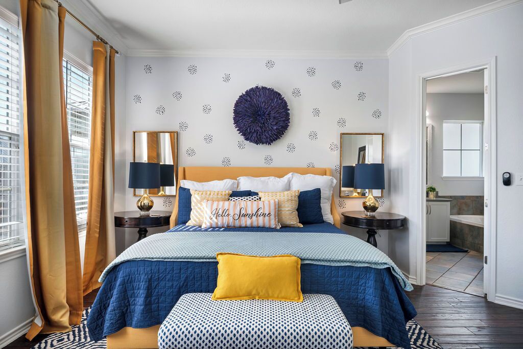 A bedroom with a large bed, two bedside tables, a round wall decoration, and a view of the outside.