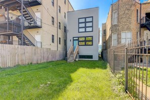 Un bâtiment moderne doté d’un toit plat, d’un petit jardin devant et d’une clôture en bois.