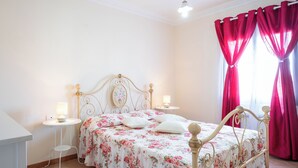 Un dormitorio con una cama, dos mesitas de noche y una ventana con cortinas.