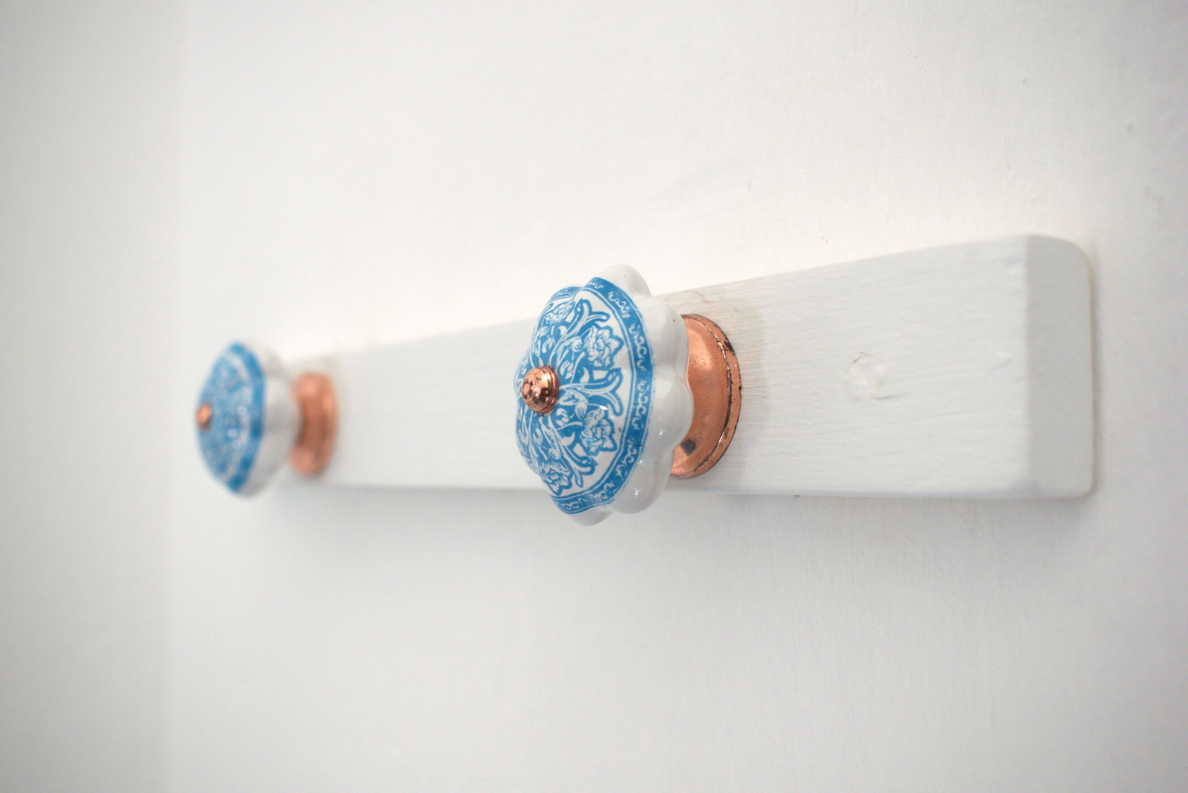 Een witte muur met drie decoratieve wandhaken.