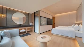A modern hotel room with a sofa, a bed, a round table, and a large mirror.