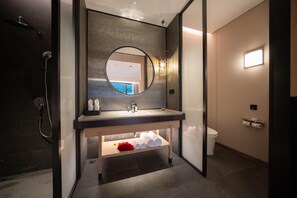 A modern bathroom with a dark-toned sink, a round mirror, and a shower area. - Madison Hot Spring Hotel Jian Wugong Mountain (Ji'an)