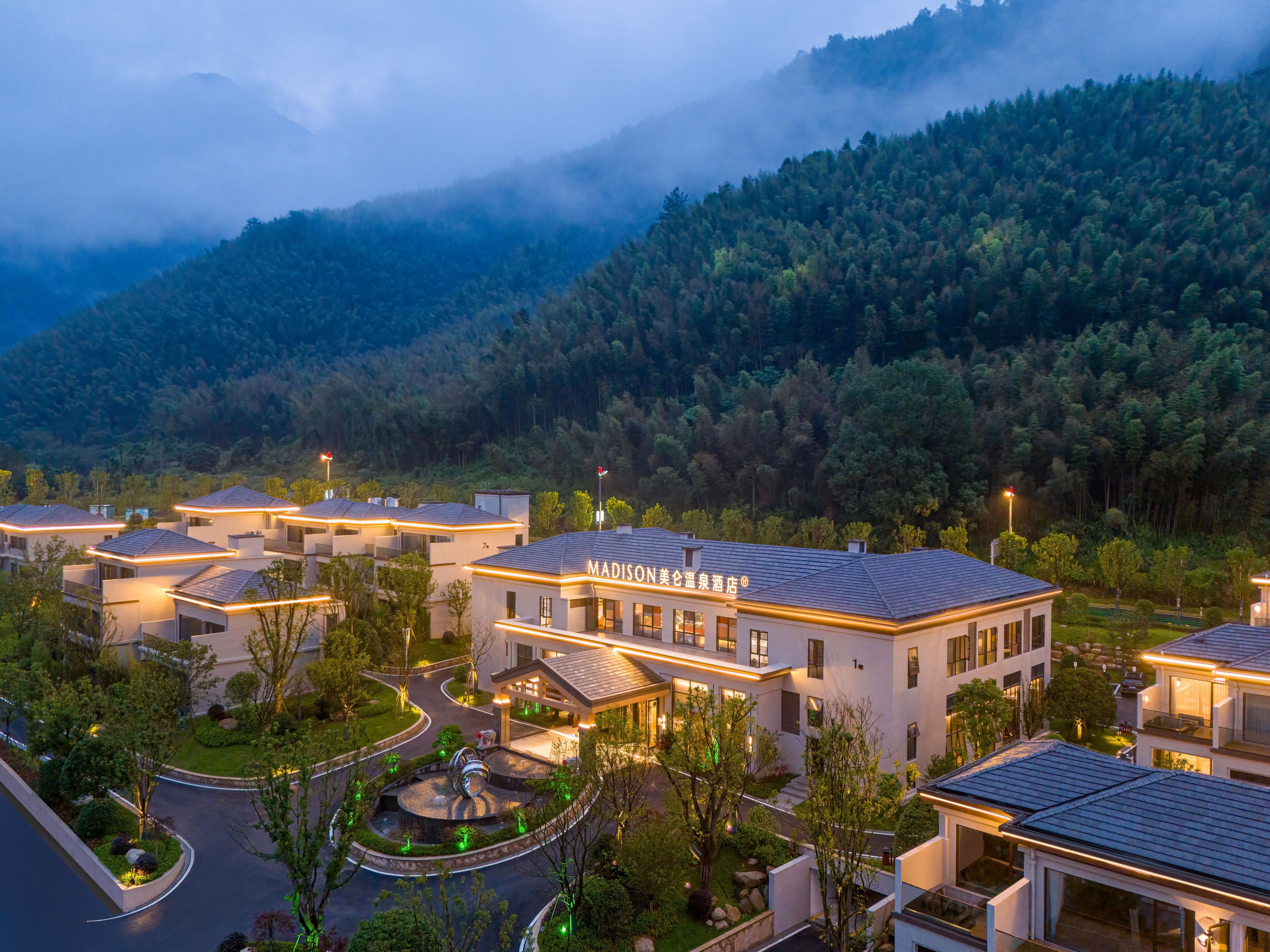 A modern hotel with a central courtyard, surrounded by lush greenery and mountains.