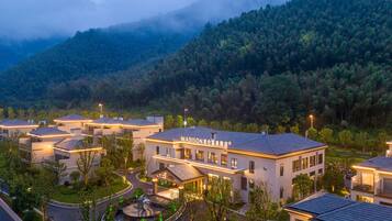 Um hotel moderno com um pátio central, rodeado por vegetação exuberante e montanhas.
