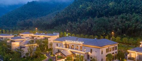 A modern hotel with a central courtyard, surrounded by lush greenery and mountains.