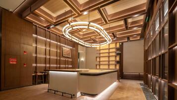 Um lobby moderno com uma receção central, painéis de madeira e um design de teto único.