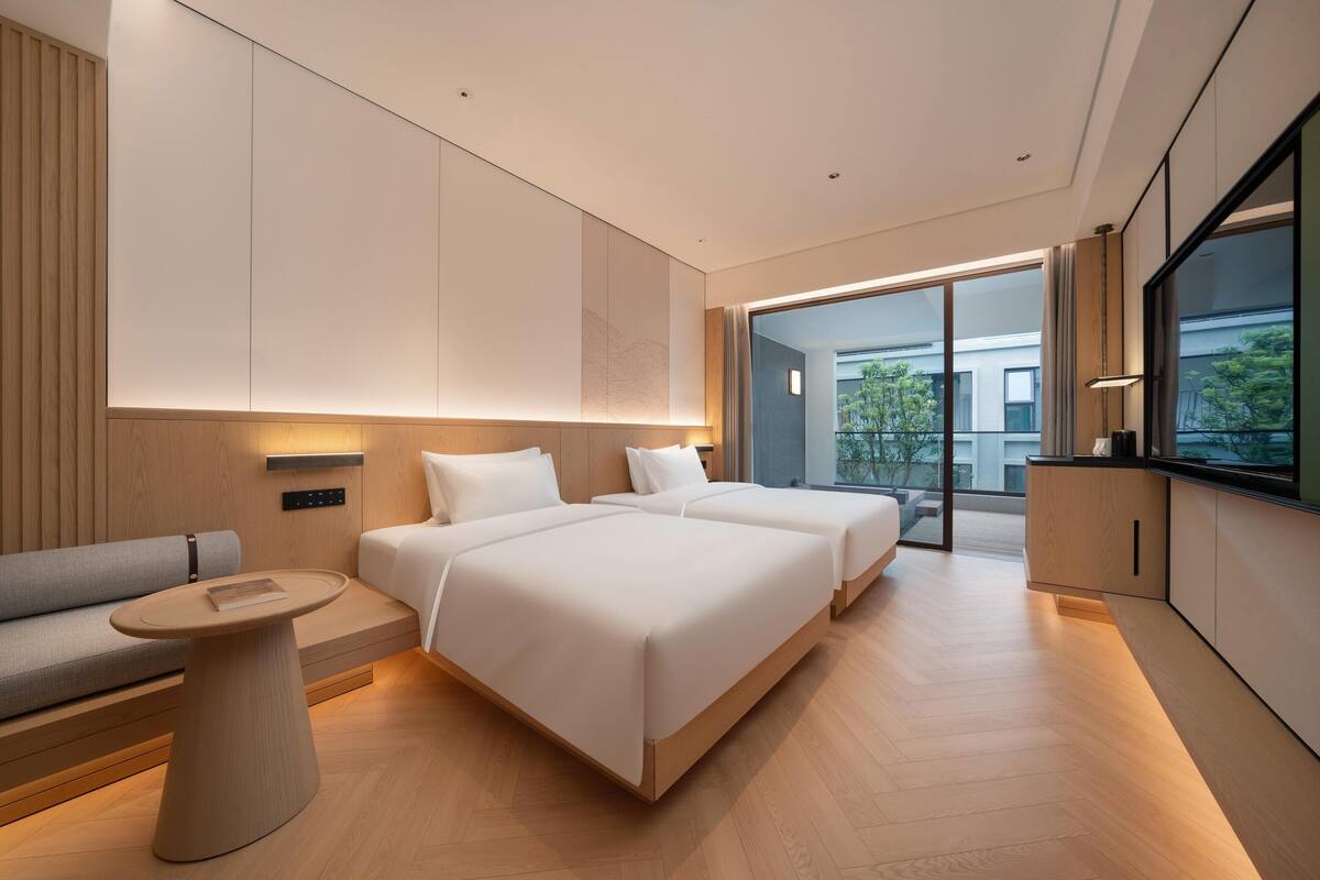 A modern hotel room with a large bed, a sofa, a small table, and a TV.