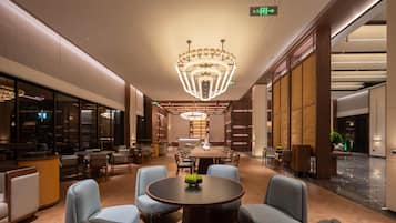 A spacious lobby with a large chandelier, comfortable seating, and a reception area.