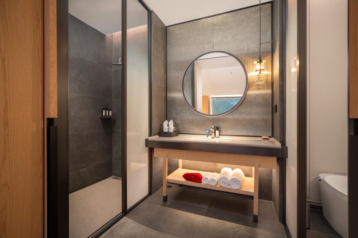 A modern bathroom with a large mirror, a wooden vanity, and a shower area.