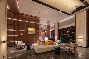 A modern lobby with a sofa, chairs, a coffee table, and a reception desk.