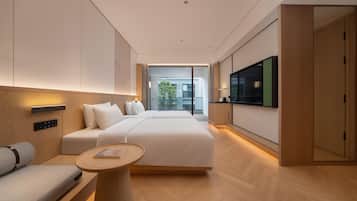 A modern hotel room with a large bed, a seating area with a small table, and a TV mounted on the wall.