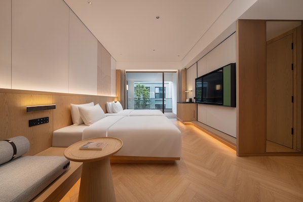 A modern hotel room with a large bed, a seating area with a small table, and a TV mounted on the wall. - Madison Hot Spring Hotel Jian Wugong Mountain (Ji'an)