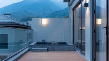 A modern building with a wooden deck, a stone planter, and a view of mountains.