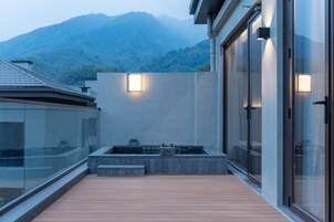 A modern building with a wooden deck, a stone planter, and a view of mountains.