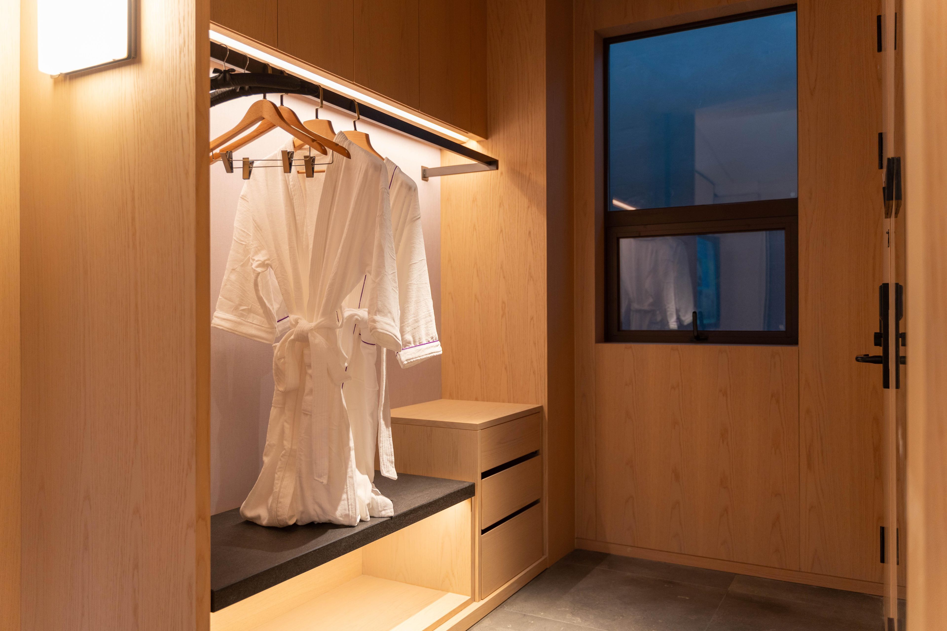 A walk-in closet with wooden cabinetry, a hanging rack, and a window with a view.