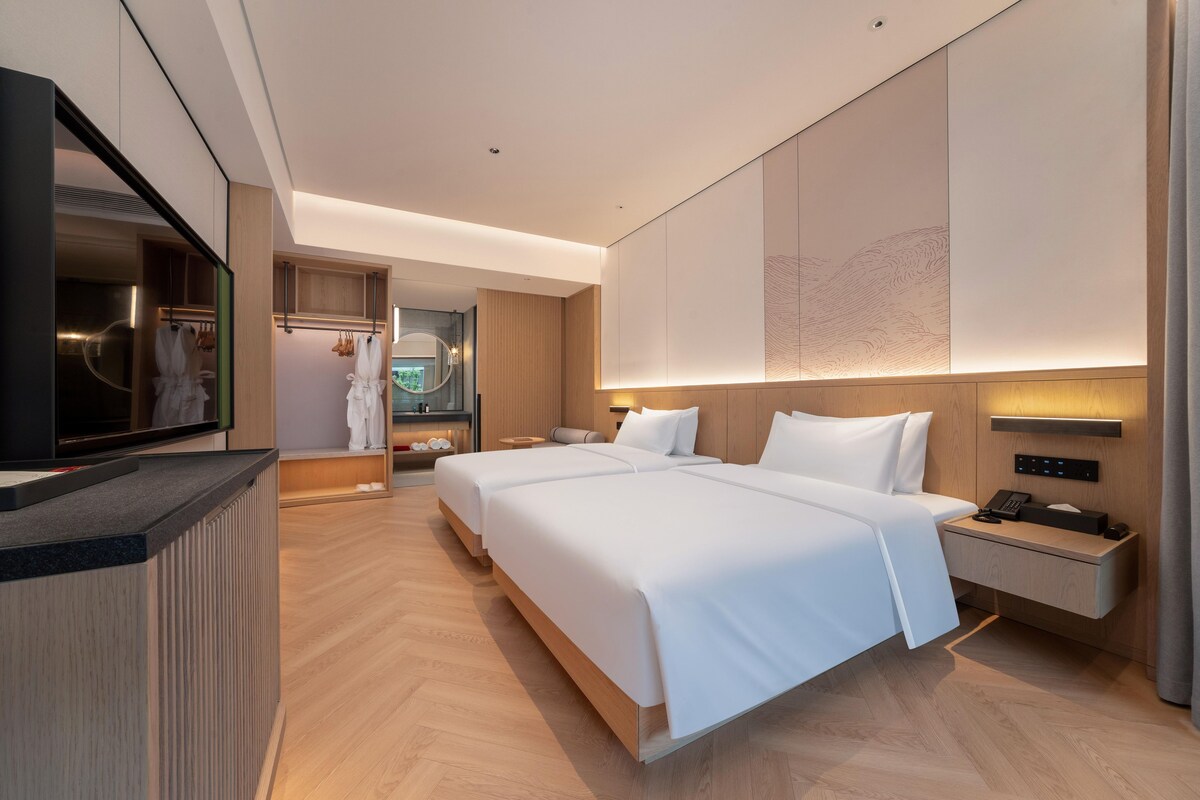 Et moderne hotelværelse med en stor seng, et sengebord med telefon og et indbygget fjernsyn.