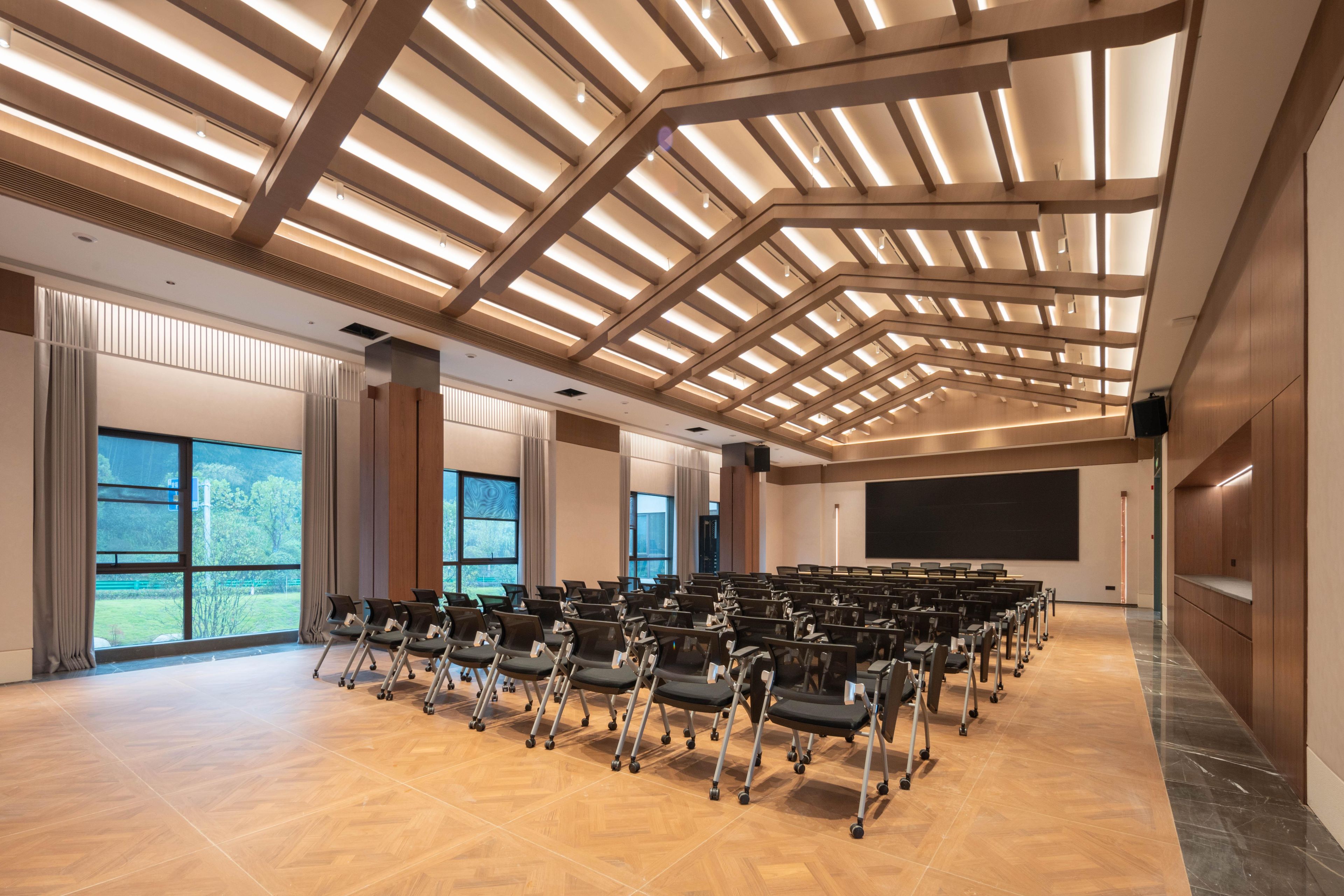 Una amplia sala de conferencias con asientos escalonados, ventanas grandes y un diseño moderno de techo.
