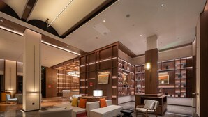 A modern lobby with a seating area, a reception desk, and a bookshelf filled with books. - Madison Hot Spring Hotel Jian Wugong Mountain (Ji'an)