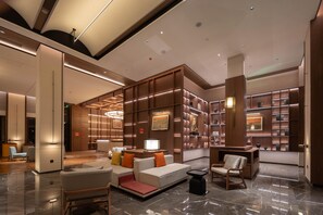 A modern lobby with a seating area, a reception desk, and a bookshelf filled with books. - Madison Hot Spring Hotel Jian Wugong Mountain (Ji'an)