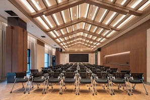 A conference room with rows of chairs, a large screen, and a modern ceiling design. - Madison Hot Spring Hotel Jian Wugong Mountain (Ji'an)
