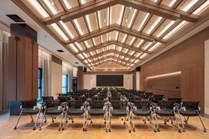 A conference room with rows of chairs, a large screen, and a modern ceiling design.