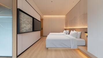 A modern hotel room with a minimalist design, featuring a large bed, a flat-screen TV mounted on the wall, and a large abstract painting.