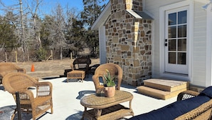 Un patio exterior con mobiliario de mimbre, un muro de piedra y una puerta.