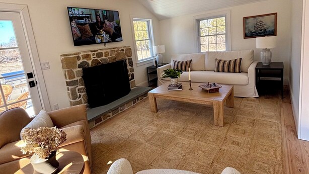 Una sala de estar con chimenea de piedra, vigas de madera, televisor, sofá y mesa de centro.