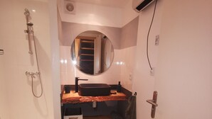Een badkamer met douche, wastafel, spiegel en handdoekrek.