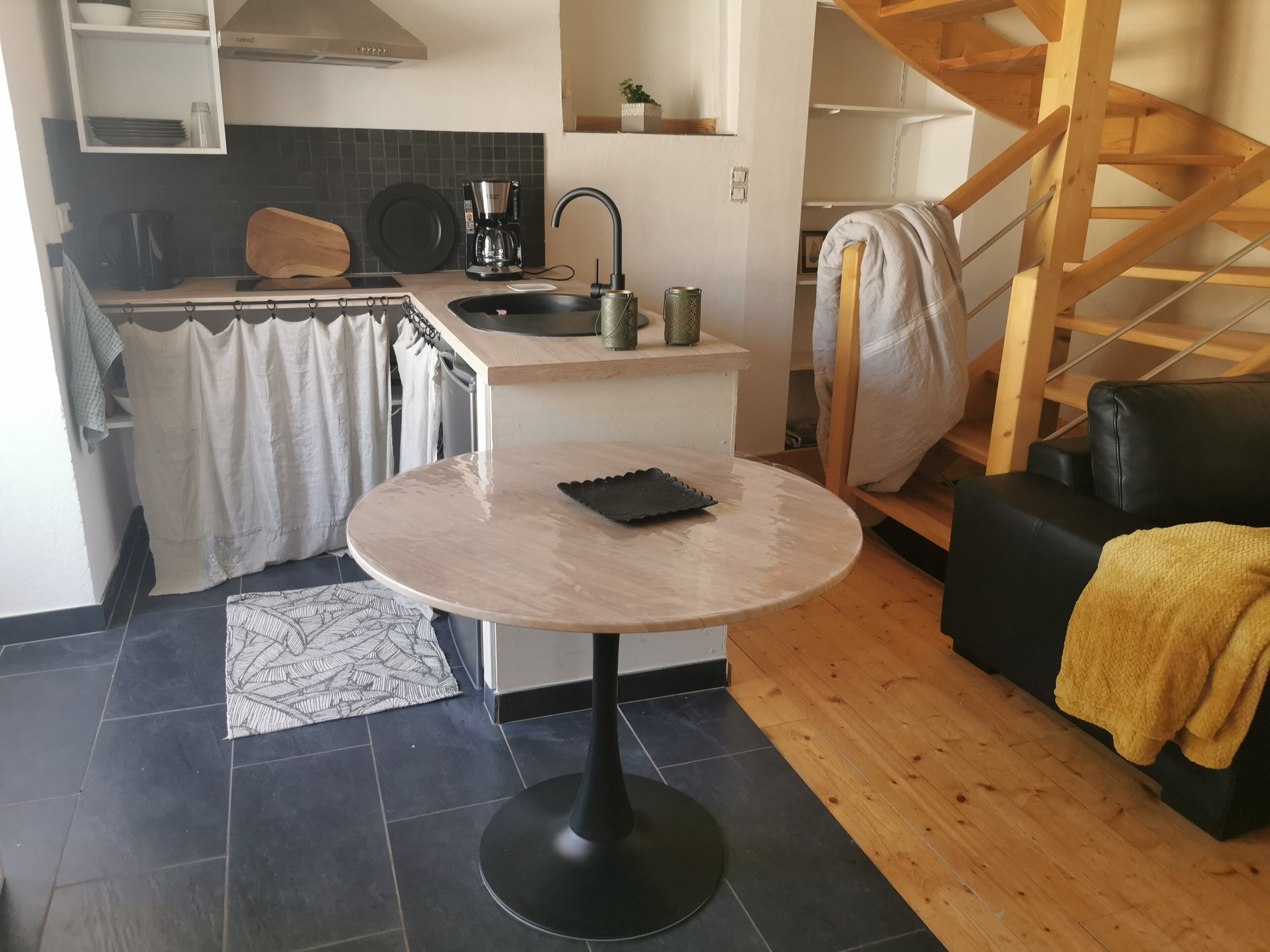 A compact living space with a kitchen area, a dining table, and a staircase.