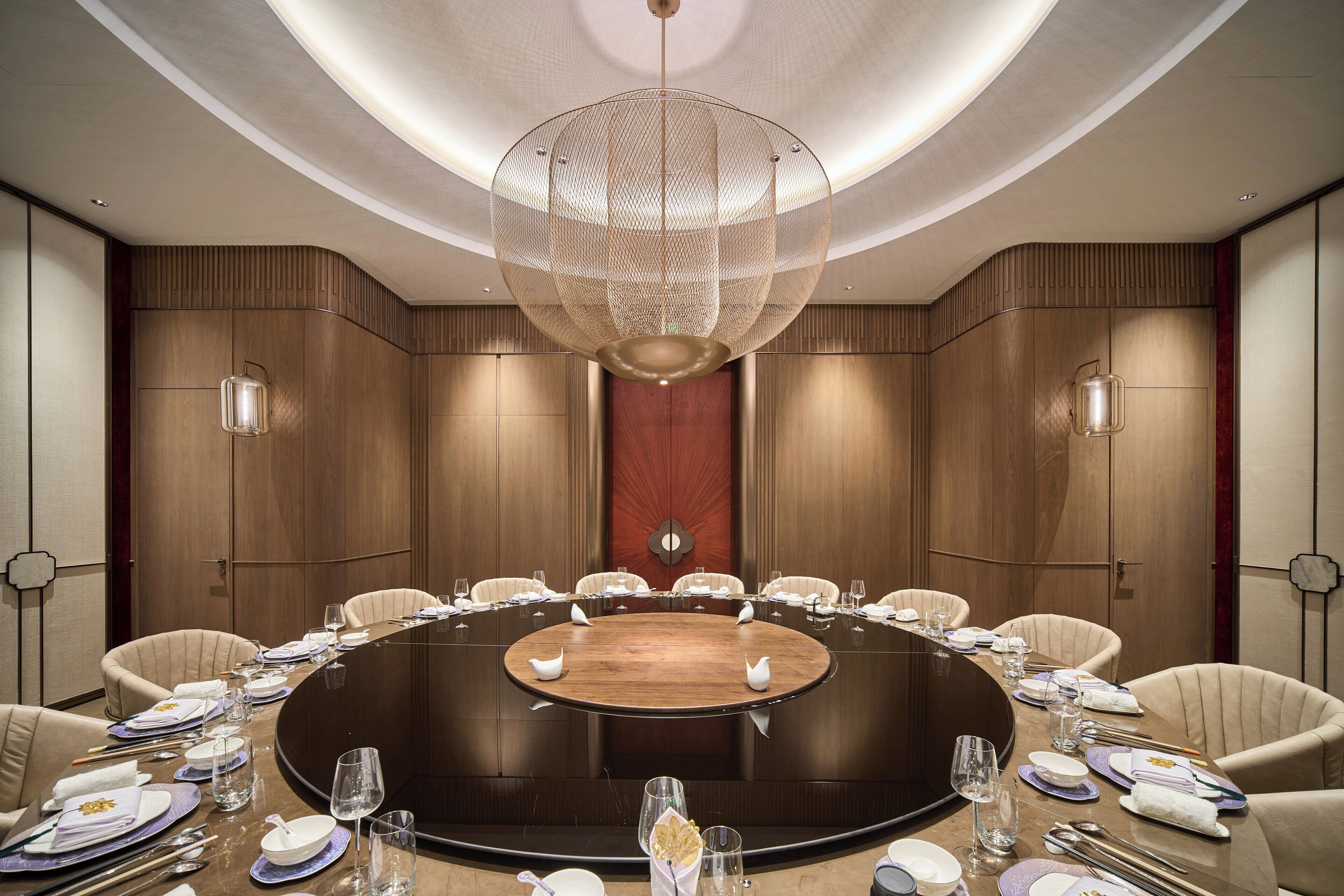 A conference room with a round table, chairs, and a large chandelier.