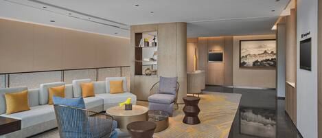 A modern living room with a sofa, armchairs, a coffee table, and a rug.
