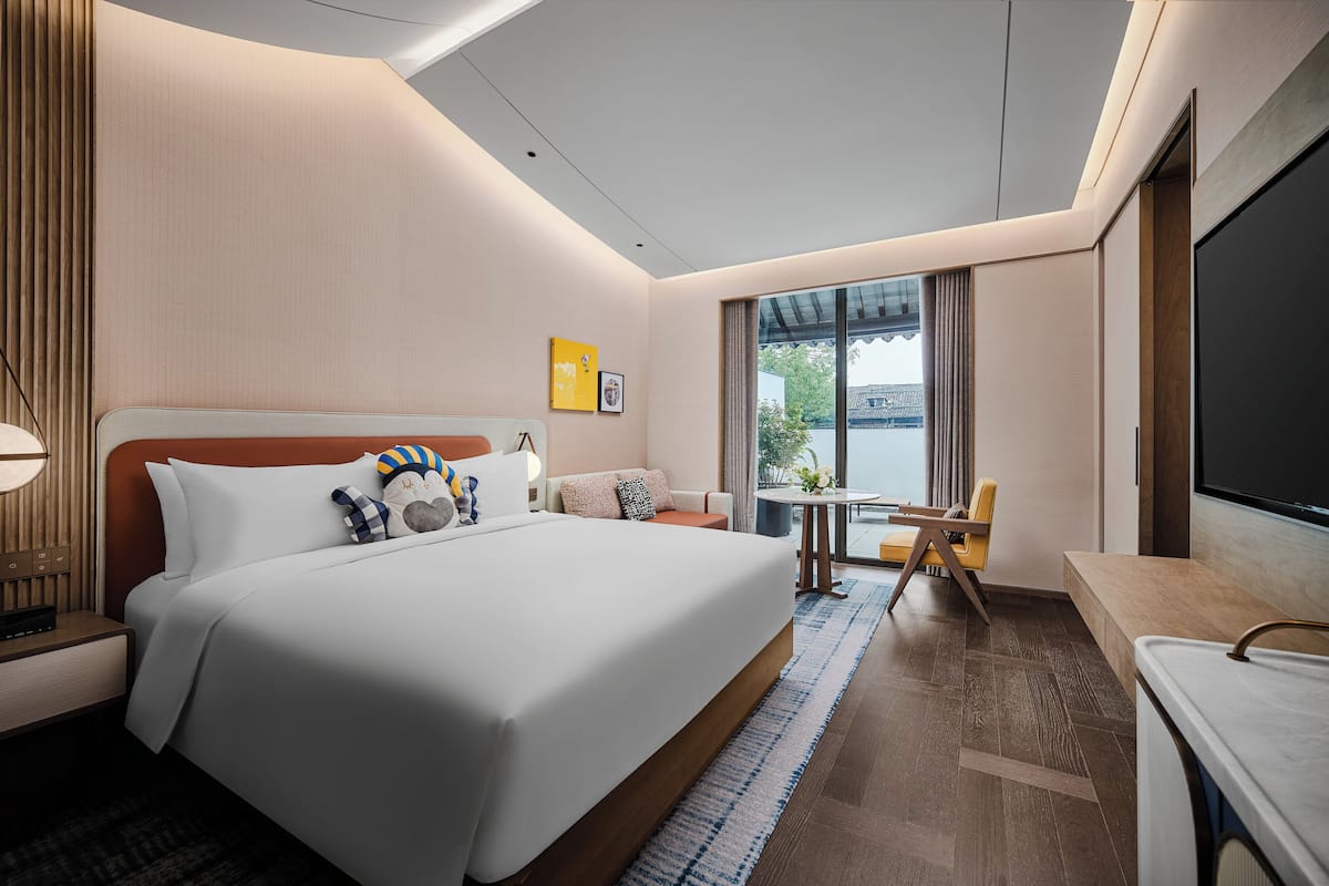 Ett modernt hotellrum med en stor säng, ett skrivbord, en stol och en tv.