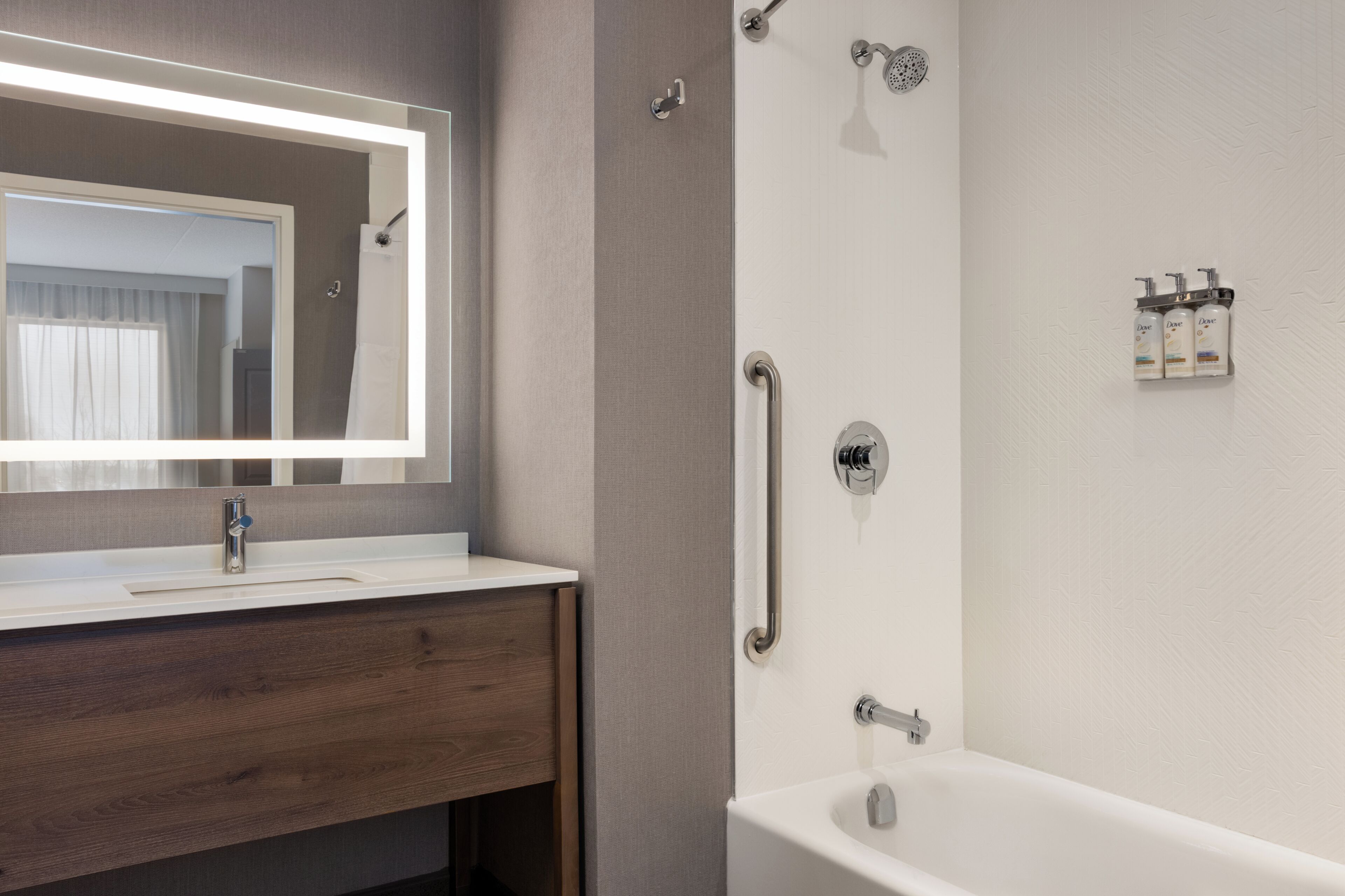Een moderne badkamer met een witte wastafel, spiegel en bad.