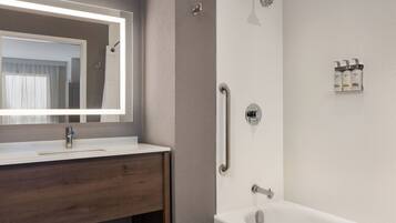 A modern bathroom with a white sink, mirror, and bathtub.