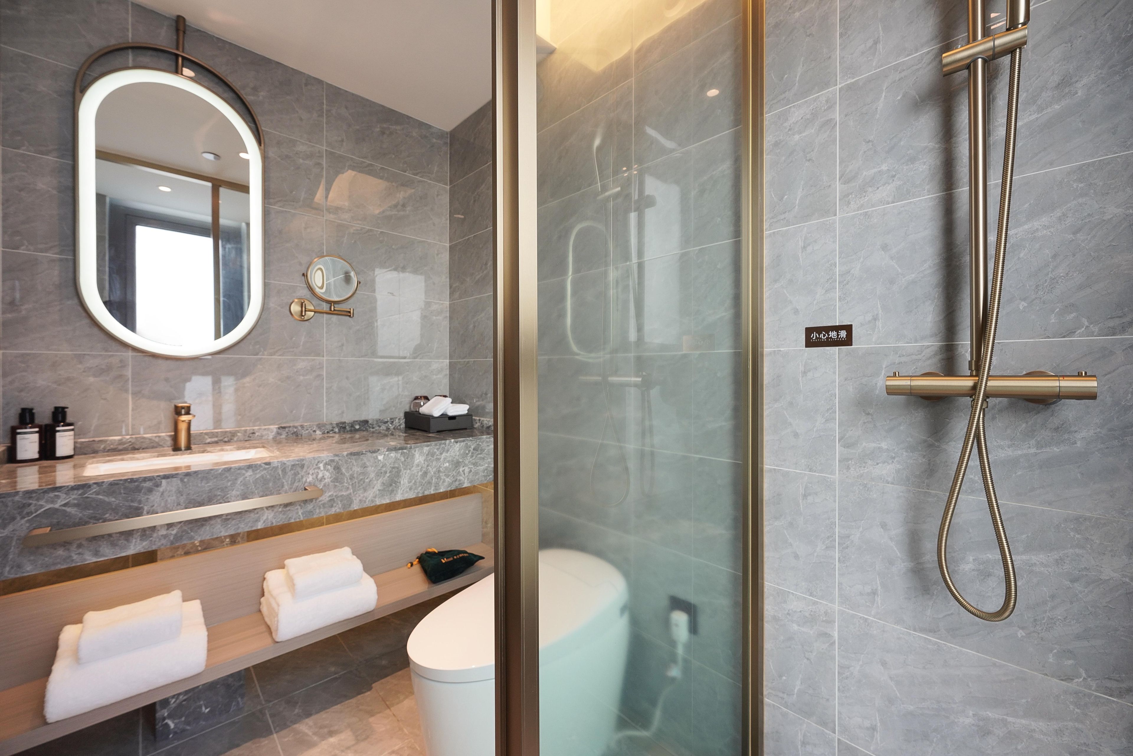 Une salle de bain moderne avec une douche à parois de verre, un lavabo en marbre et un grand miroir.