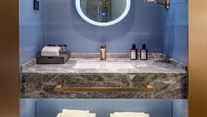 Un baño con lavamanos de mármol, un espejo y un perchero para toallas.
