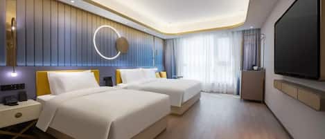 Une chambre d’hôtel moderne équipée de deux lits, d’une télévision, d’une table de chevet et d’un luminaire rond.