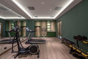 Un gimnasio con equipo de ejercicio, un espejo y una banca.
