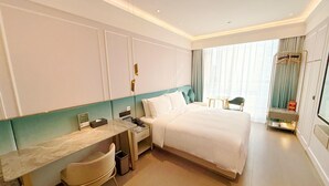 Ein Hotelzimmer mit Bett, Schreibtisch, Stuhl, kleinem Tisch, Spiegel und Kleiderschrank.