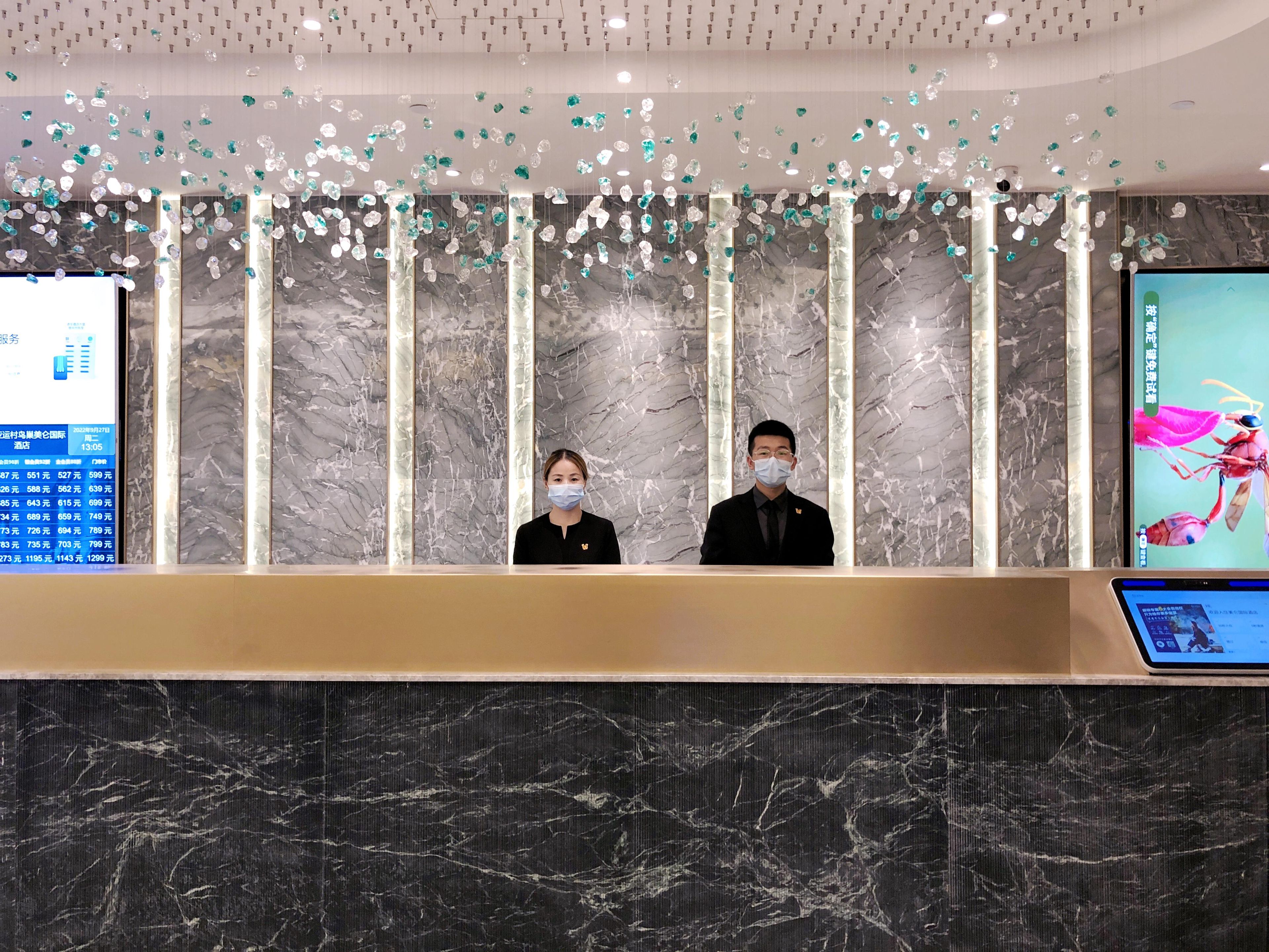 A reception desk with a marble wall and a digital screen displaying information.