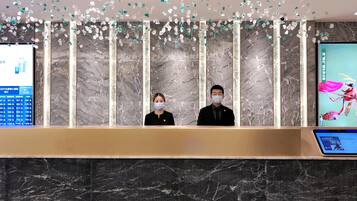 A reception desk with a marble wall and a digital screen displaying information.
