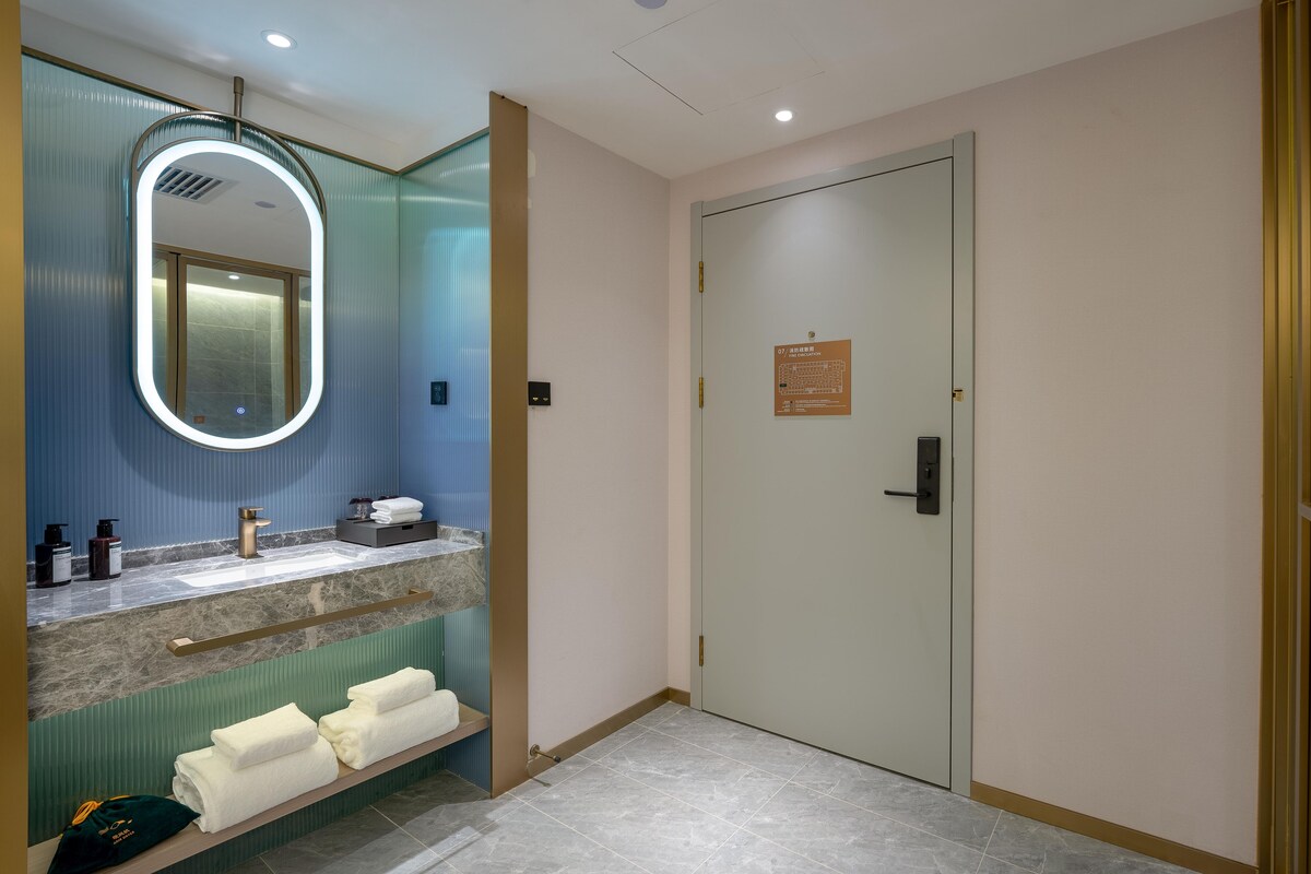 Un baño con espejo, lavamanos, toallero y una puerta con un letrero.
