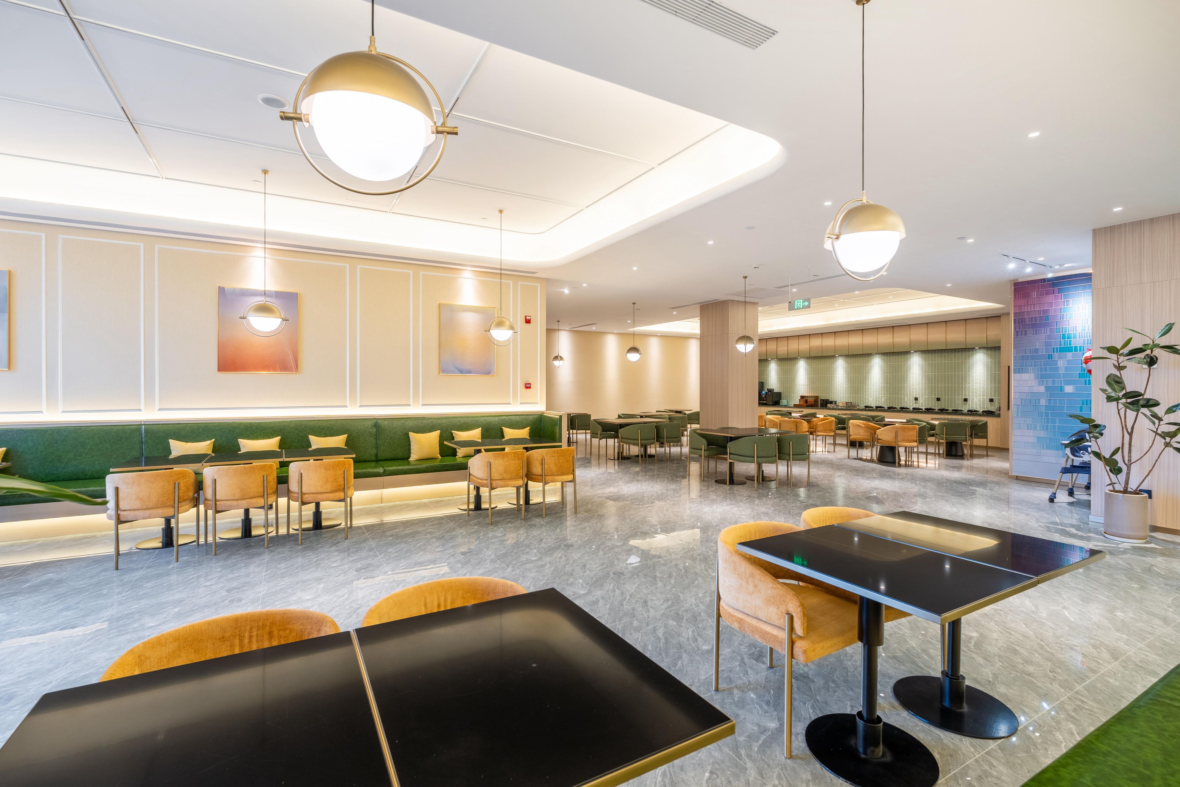 Un hall d’hôtel moderne, doté d’espaces aménagés avec des sièges, d’un espace repas et d’un panneau de signalisation indiquant clairement la sortie.