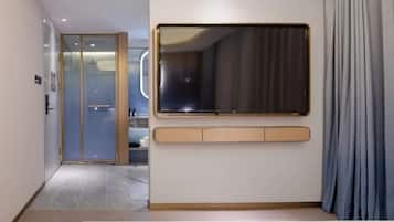 A modern hotel room with a large window, a built-in desk, and a sliding glass door leading to a bathroom.